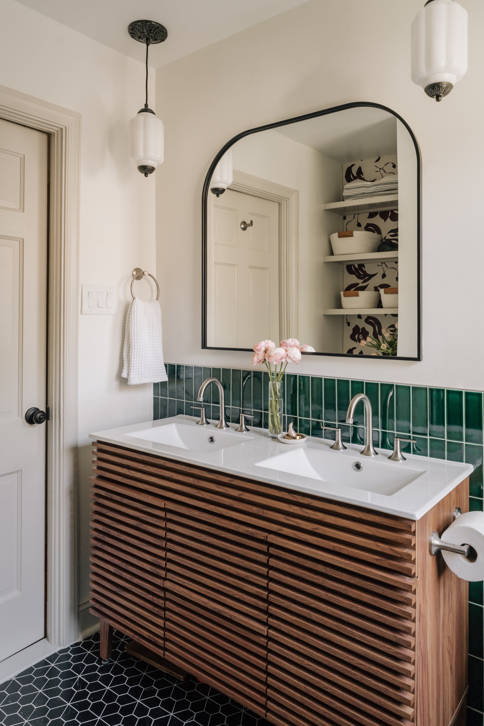 Bathroom with wooden vanity, white sinks, and emerald green tiled wall black and white pattern tile floor