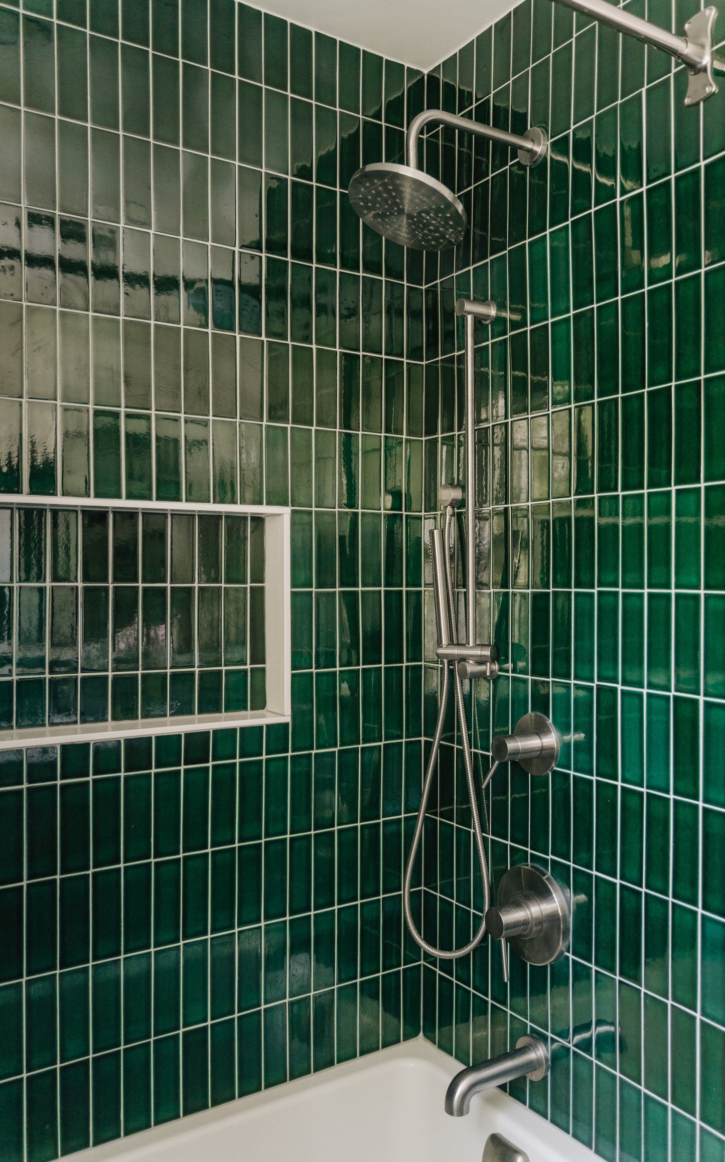 Shower setup with emerald green tiles in a bathroom silver hardware