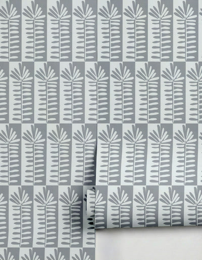 Gray and white botanical wallpaper by Clay Imports, featuring stylized leaf patterns in alternating columns, partially unrolled.