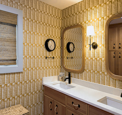 Bathroom with patterned yellow wallpaper, double sink vanity, and decorative mirror.