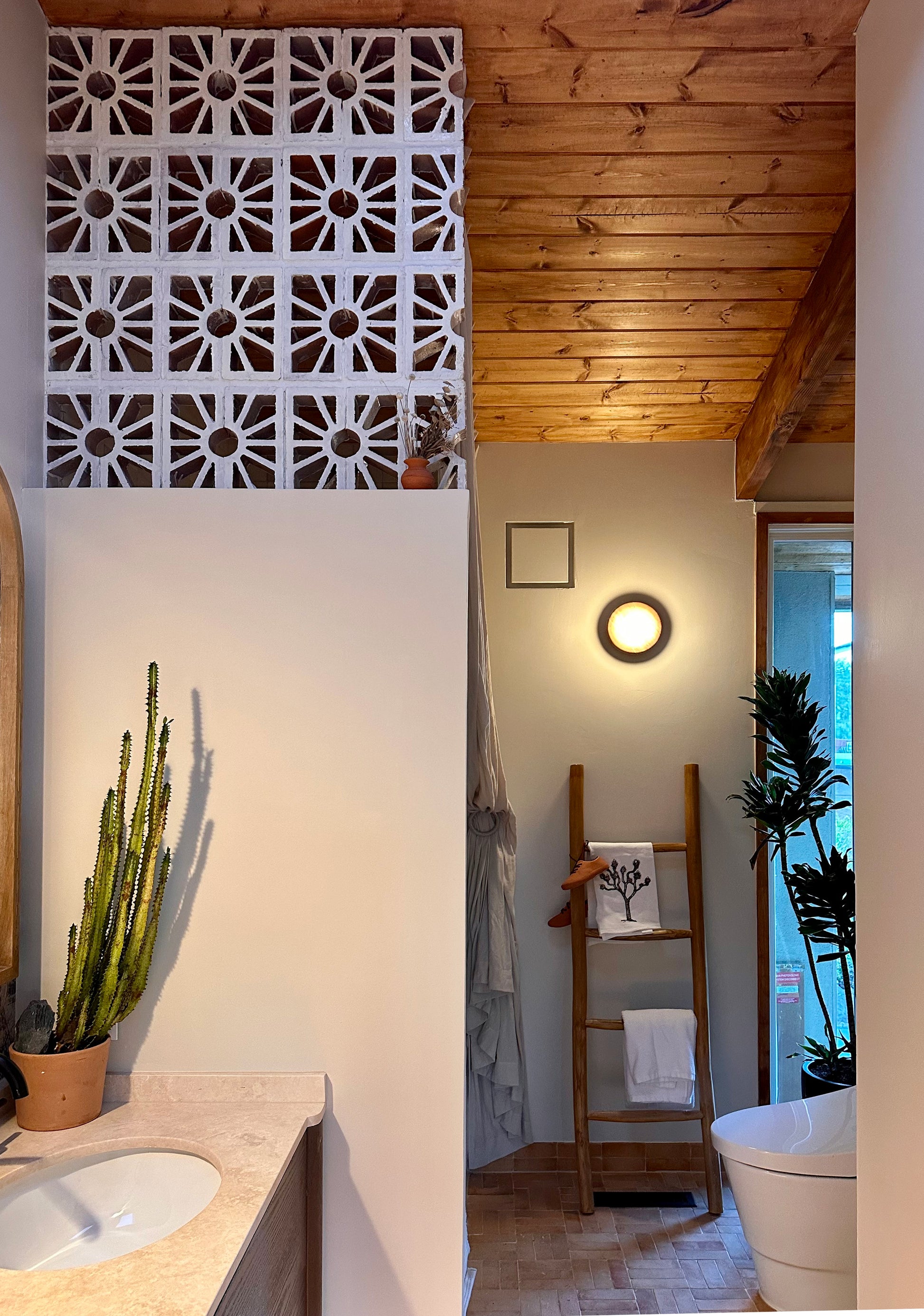 Glazed white breeze block by Clay Imports Breeze Blocks with a floral sunburst pattern, forming a decorative wall in a modern bathroom.