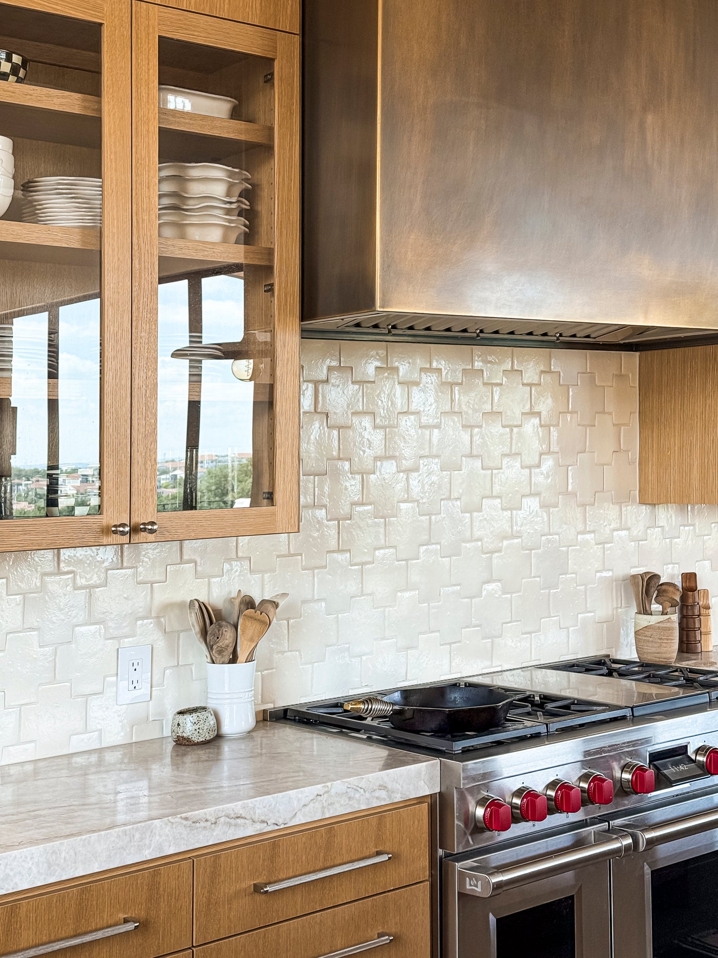 Off-white glazed terracotta tiles by Clay Imports, forming a repeating Swiss Cross pattern with a handcrafted, glossy texture, as a kitchen backsplash.