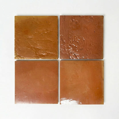 Four natural terracotta sample tiles with gloss and satin finishes from Clay Imports, showing textured and smooth surfaces.