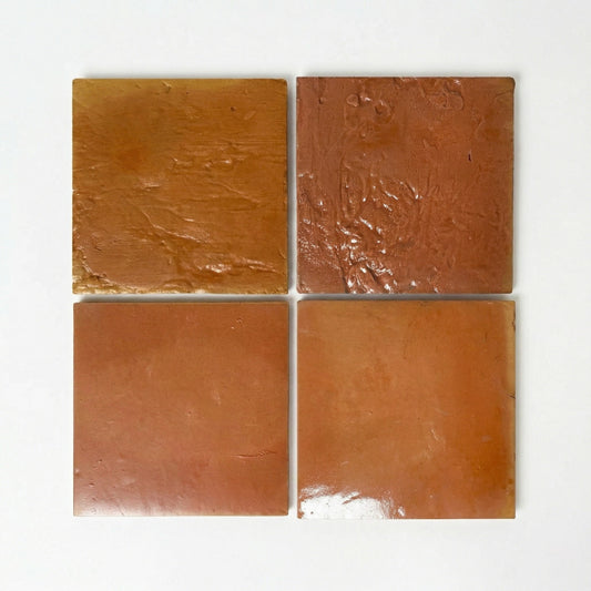 Four natural terracotta sample tiles with gloss and satin finishes from Clay Imports, showing textured and smooth surfaces.