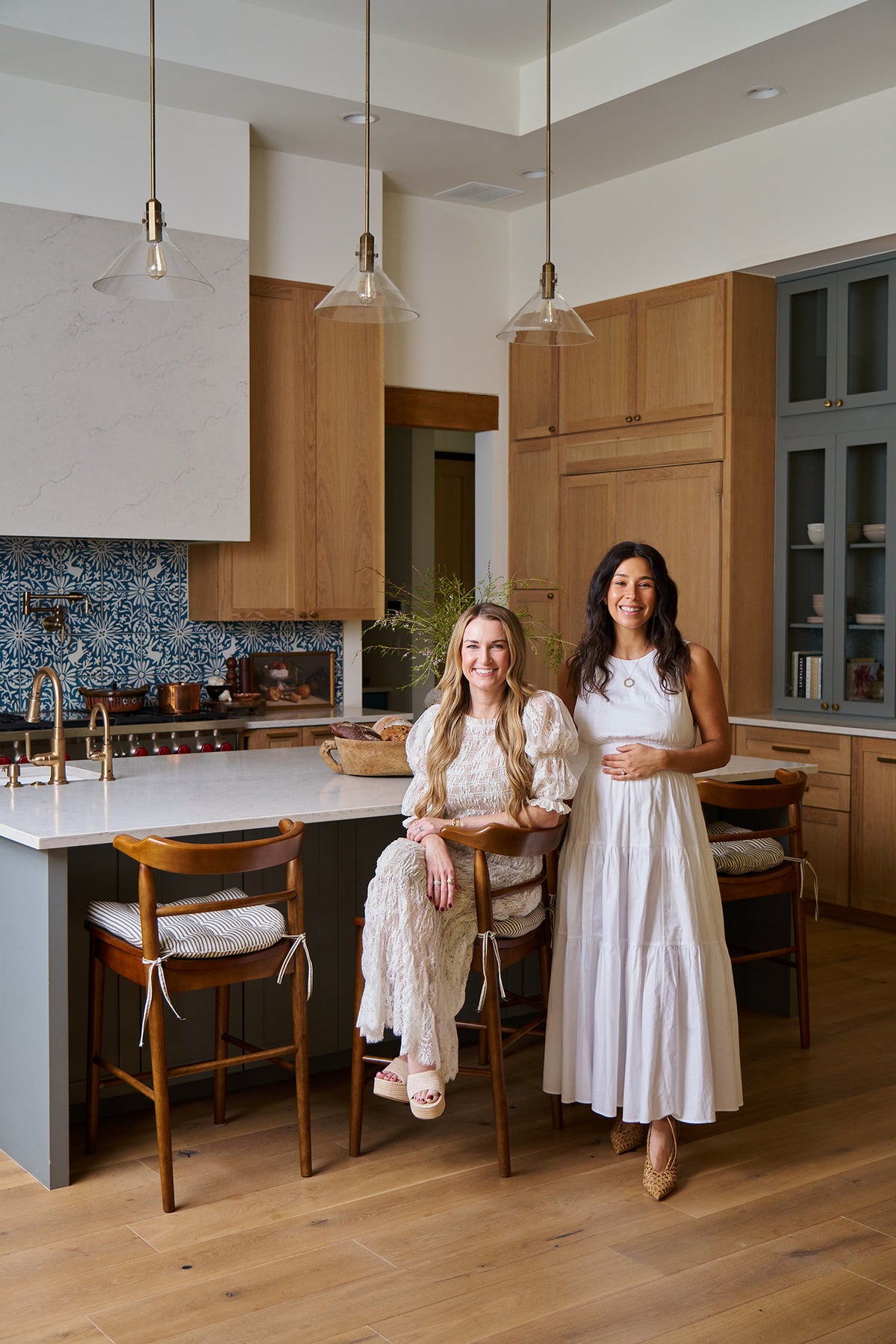 Two women, Audrey Scheck and Yovana, in a modern kitchen, one sitting at the island and the other standing.