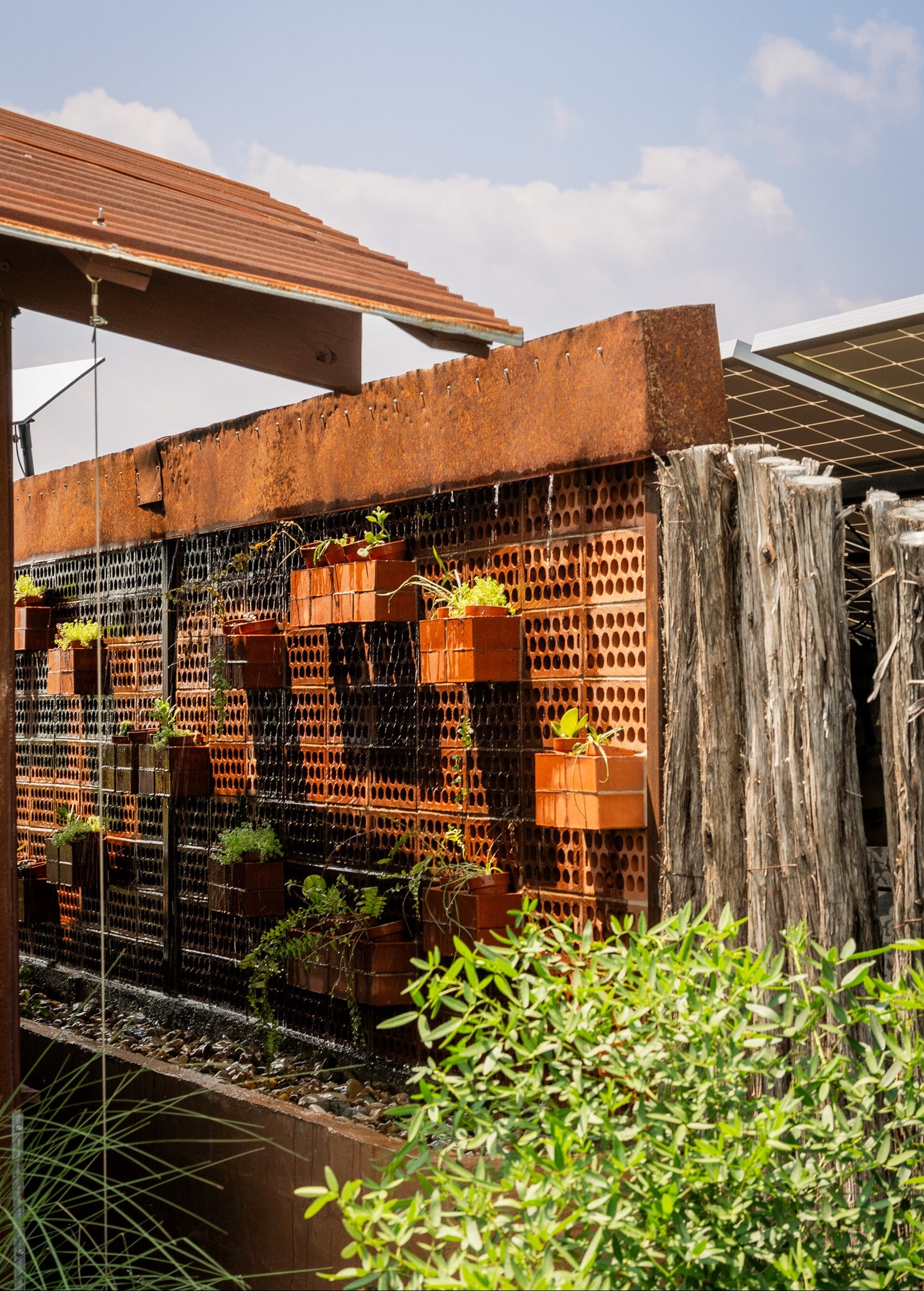 Wall with planters and solar panels on a clear day. Passive cooling wall with breeze blocks