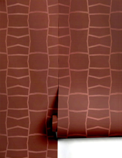 Reddish-brown wallpaper by Clay Imports featuring an abstract wobbly light pink grid pattern, with a visible seam and partially unrolled.