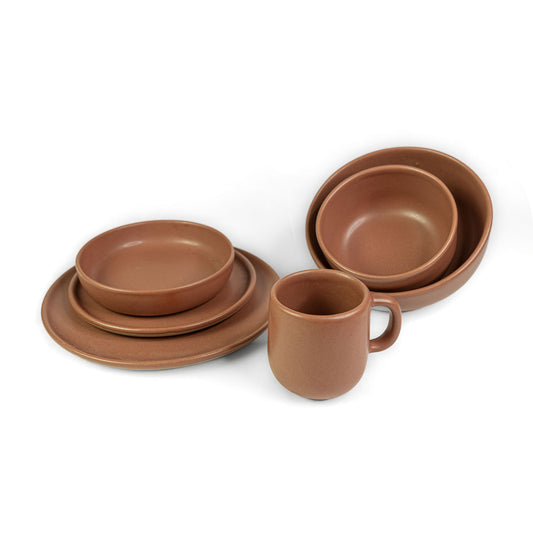 Terracotta earthenware dinnerware set by Clay Imports with stacked bowls, plates, and a mug.