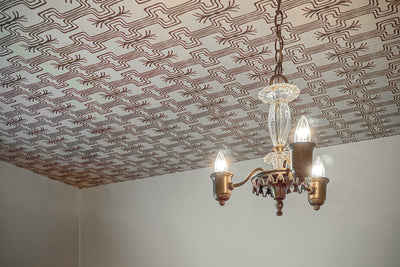 Vintage chandelier hanging from a patterned ceiling