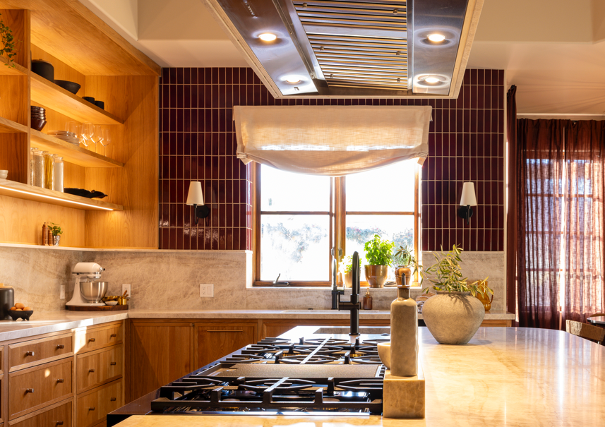 Oxblood 2x8 clay tiles by Clay Imports arranged vertically as a glossy kitchen backsplash reflecting sunlight.