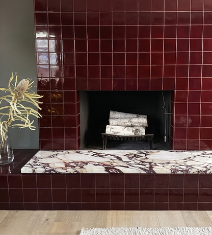 Oxblood 4.25x4.25 inch square clay tiles by Clay Imports on a modern fireplace and hearth with a marble top.
