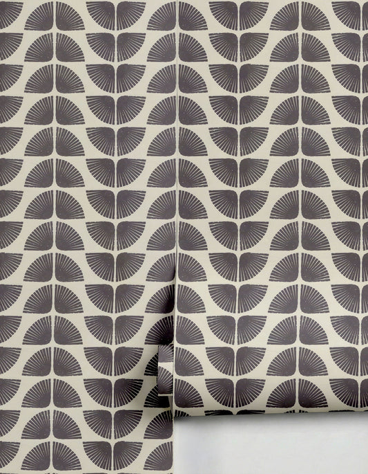 Dark grey and cream patterned wallpaper by Clay Imports featuring repeating petal fan design, partially unrolled.