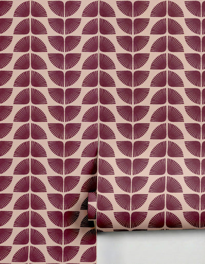 Maroon and beige patterned wallpaper by Clay Imports, featuring repeating fan motifs with a textured, block-printed look, partially unrolled.