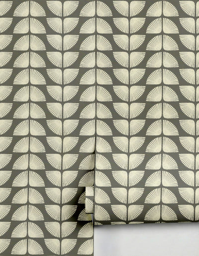 Wallpaper in grey and off-white by Clay Imports, featuring a distressed repeating petal-like pattern, partially unrolled.