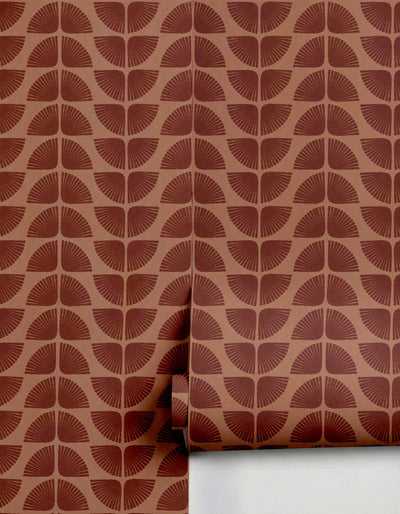 Terracotta brown Petalita wallpaper by Clay Imports with a repeating fan-like petal pattern, partially unrolled.