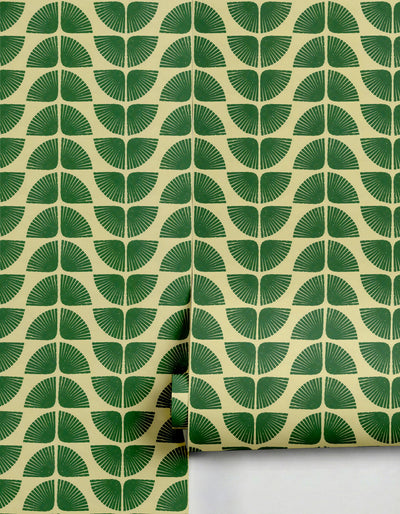 Green and beige patterned wallpaper by Clay Imports featuring repeating fan-shaped designs with a textured, block-printed look, partially unrolled.
