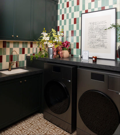 Laundry room with dark cabinets, washer, dryer, and decorative elements.