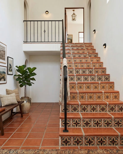 Multi-colored Relief Talavera tile by Clay Imports, featuring intricate patterns on stair risers in a warm-toned hallway.