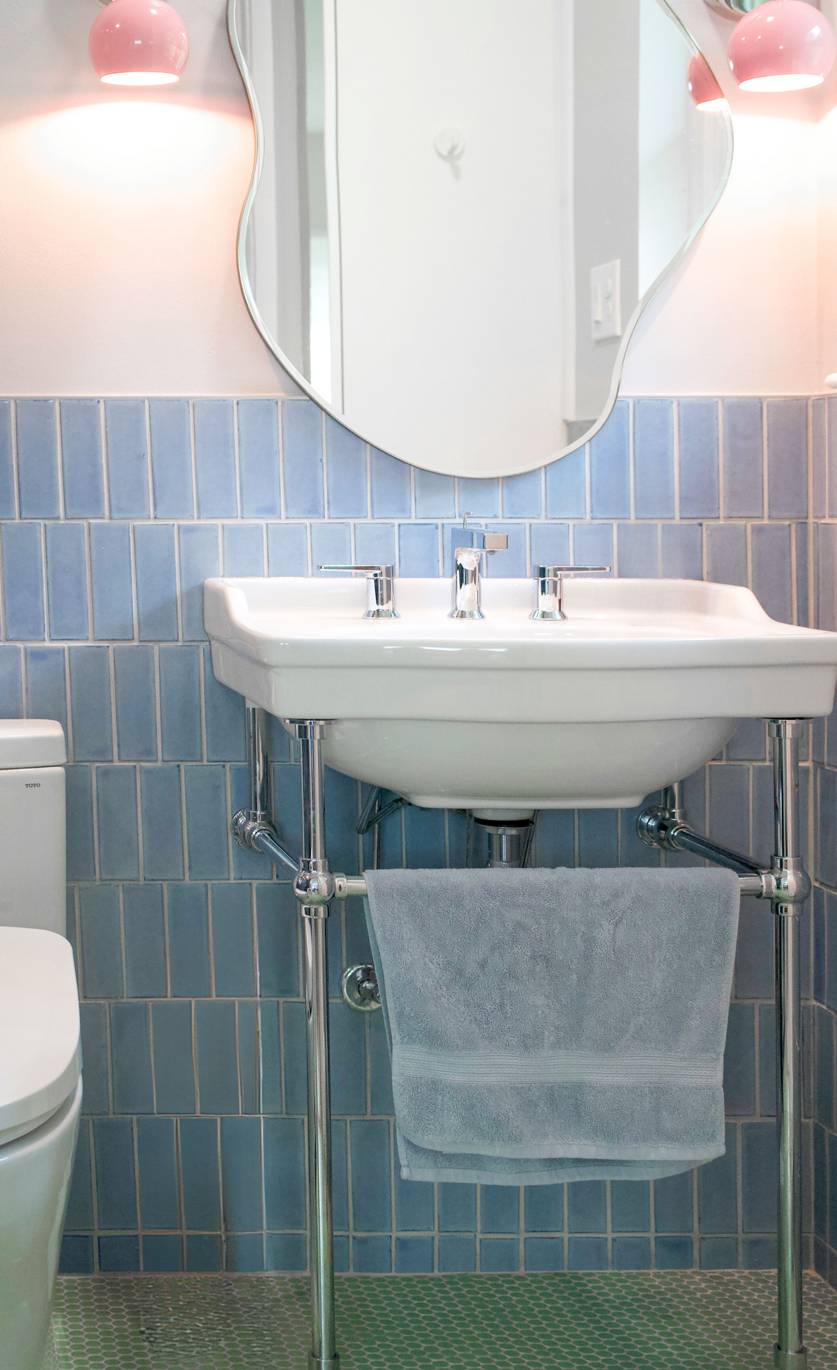 Light blue solid tile by Clay Imports in a vertical subway pattern as wainscoting behind a white bathroom sink.