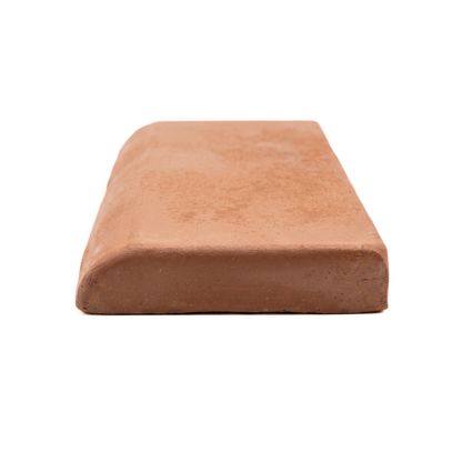 A single terracotta clay tile with a rounded top edge, shown from a low angle on a seamless white background.