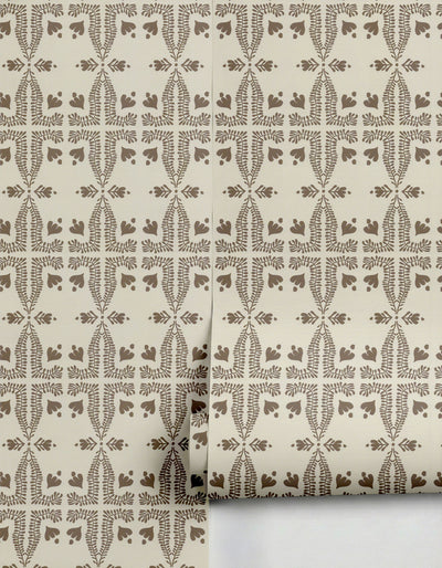 Light beige wallpaper by Clay Imports with a repeating dark brown folk art botanical pattern, partially unrolled.