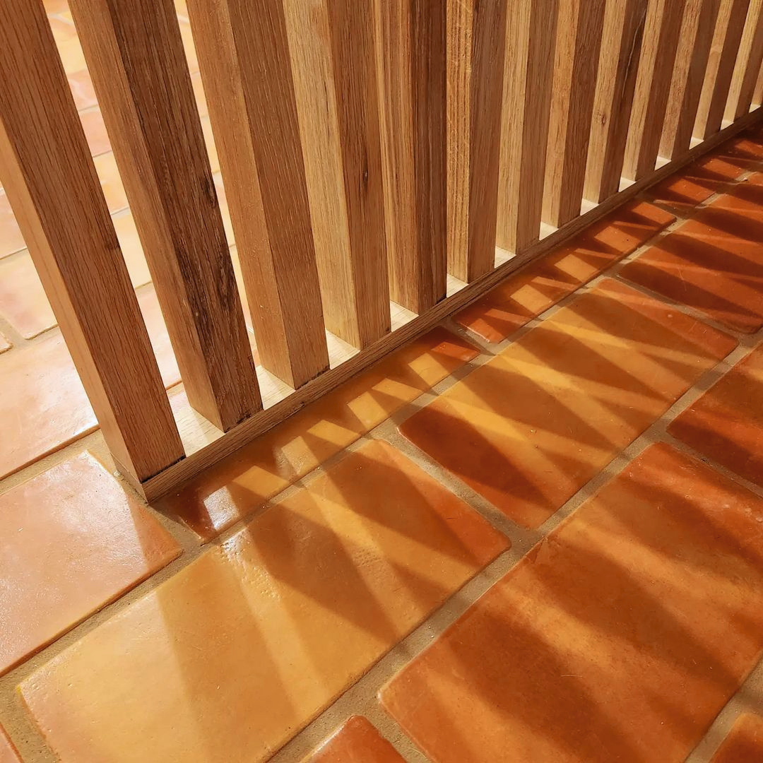 Super Smooth Gloss terracotta tile by Clay Imports, in warm rectangular orange-brown, with sunlight casting shadows.