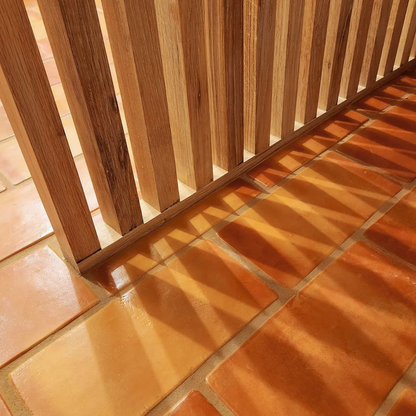 Super Smooth Gloss terracotta tile by Clay Imports, in warm rectangular orange-brown, with sunlight casting shadows.
