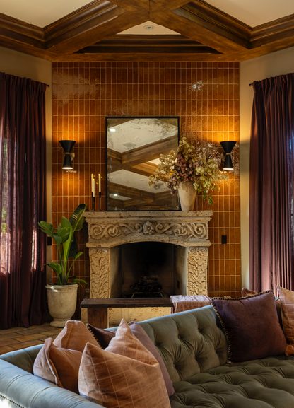 Glazed terracotta fireplace. Living room with a fireplace, couch, and decorative pillows.