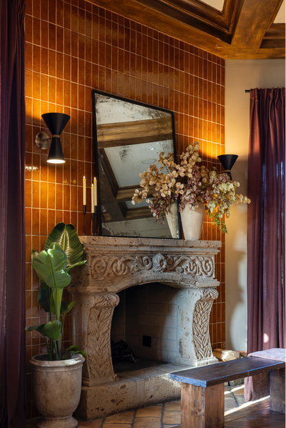 Terra crackle glazed thin brick by Clay Imports arranged vertically on a warm wall behind a carved stone fireplace.