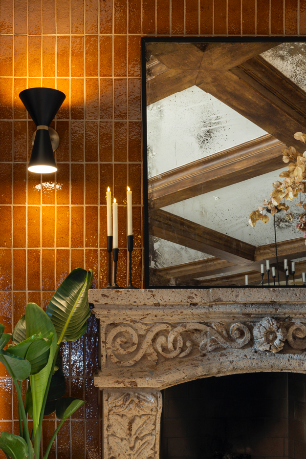 Terra Crackle Glazed Thin Brick by Clay Imports in glossy warm orange-brown, vertically installed on a wall next to a stone fireplace.