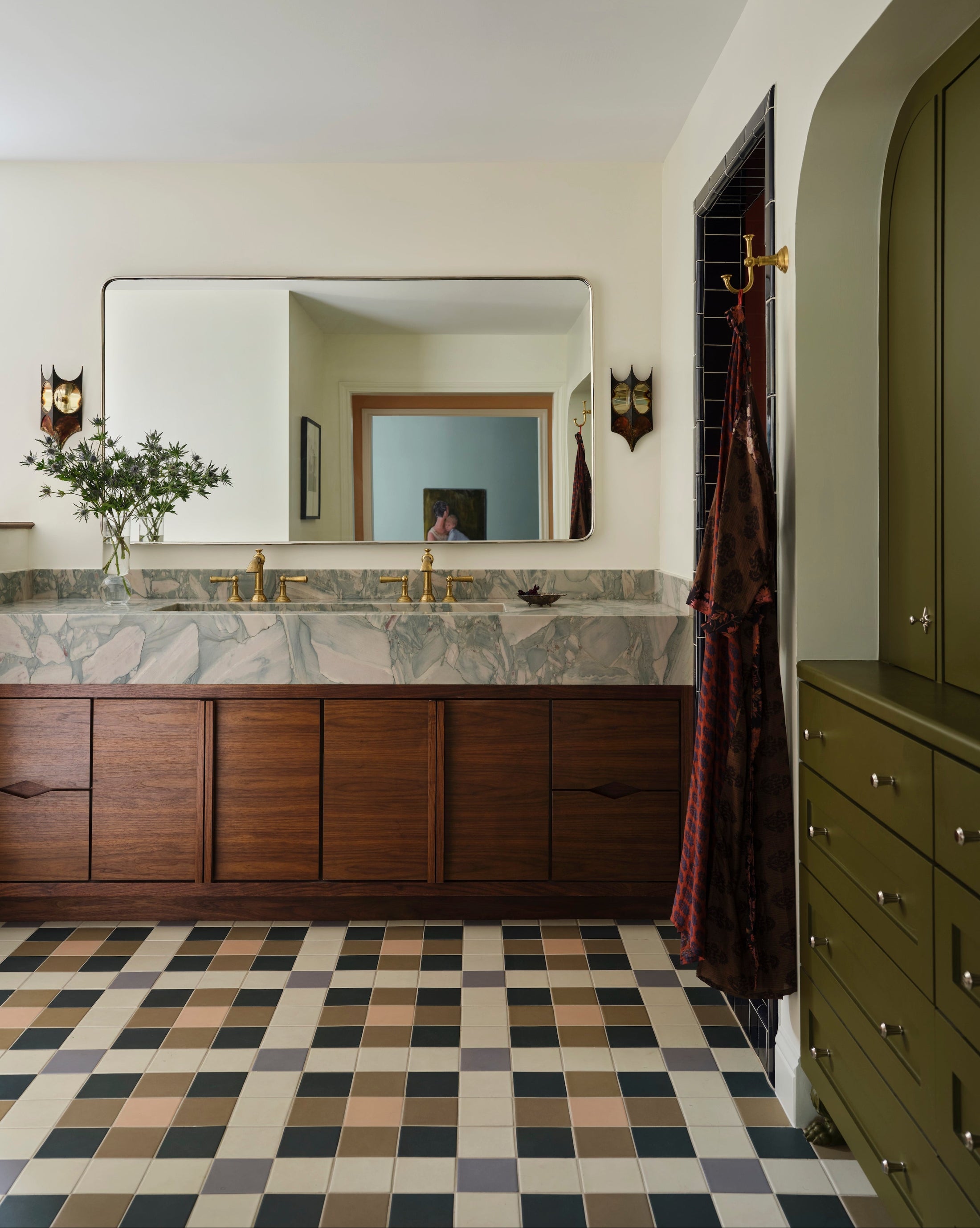 Bathroom with marble countertop, wooden cabinets, and checkered floor.