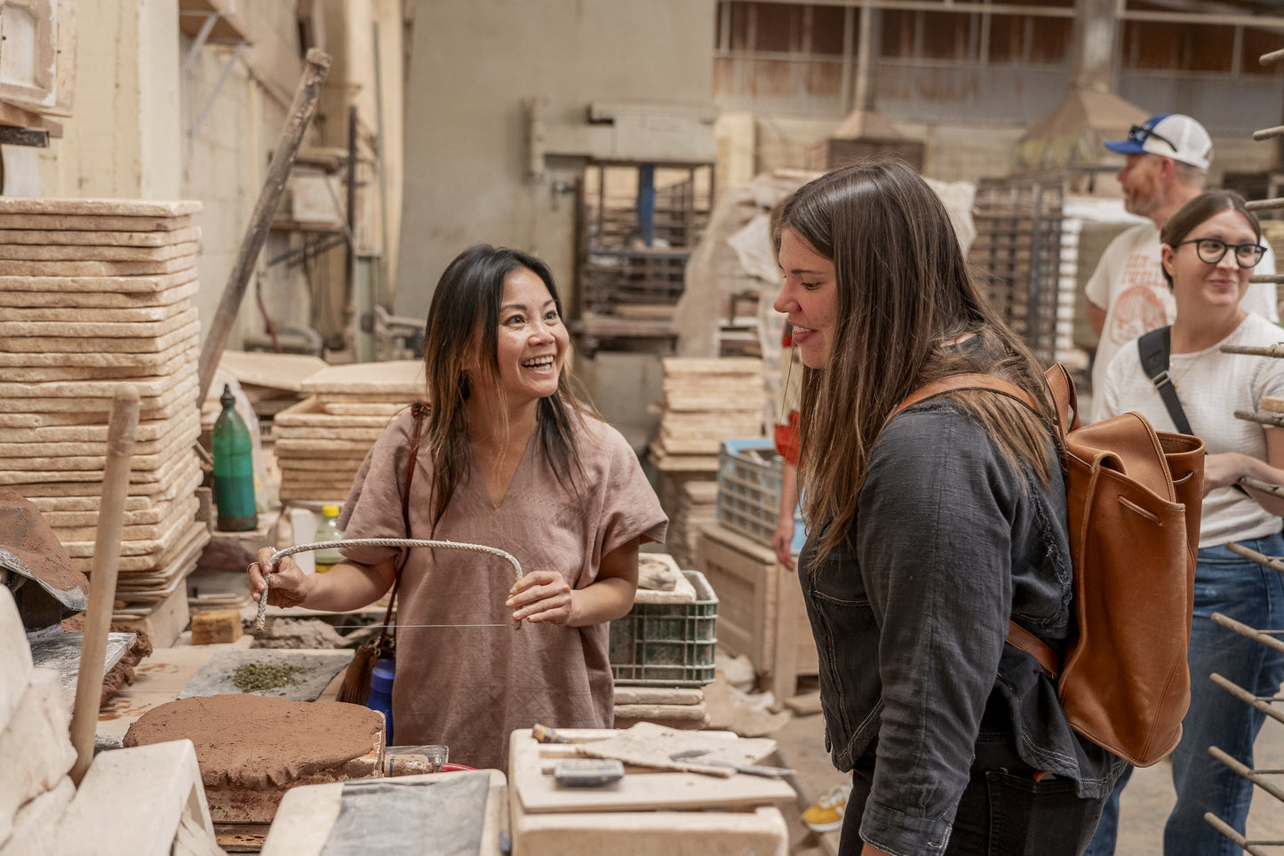 Creative tile workshop activity by Clay Imports showing two smiling women working with clay and tools.