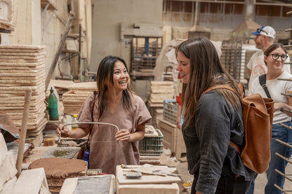 Creative tile workshop activity by Clay Imports showing two smiling women working with clay and tools.