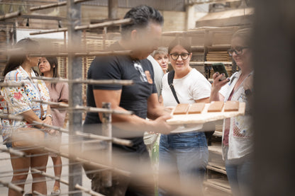 Tile Travels retreat activity from Clay Imports showing a group of people observing reddish-brown tiles on a wooden board.