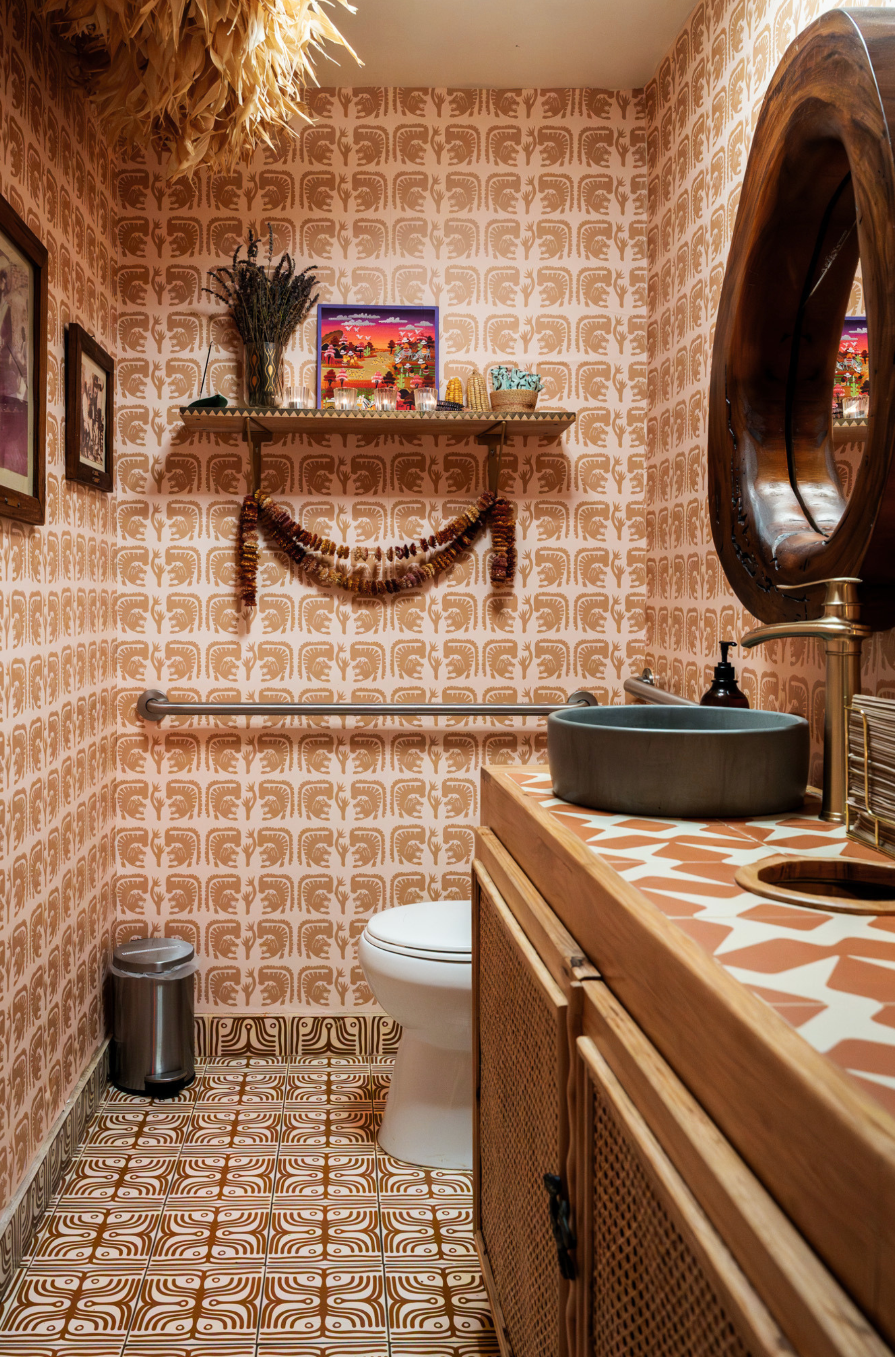 Bathroom with patterned wallpaper, wooden vanity, and decorative elements.