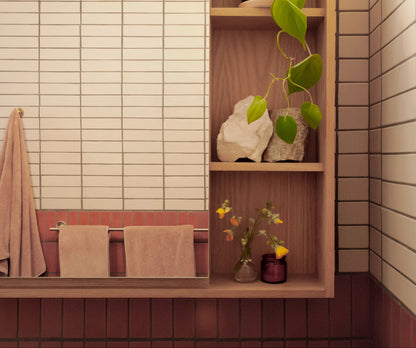 Rectangular Twine 2x8 clay tiles by Clay Imports in off-white and reddish-brown hues, styled with wood shelving and pink towels.