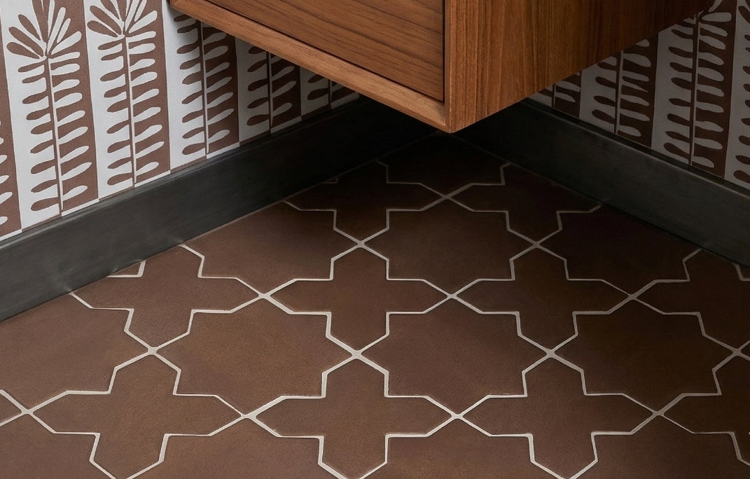 Saddle Star and Cross clay tiles by Clay Imports, arranged on a floor with white grout lines next to a dark baseboard.