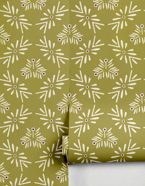 Olive green Margarita Wallpaper by Clay Imports, featuring a repeating creamy white abstract floral pattern with dark purple centers, partially unrolled.