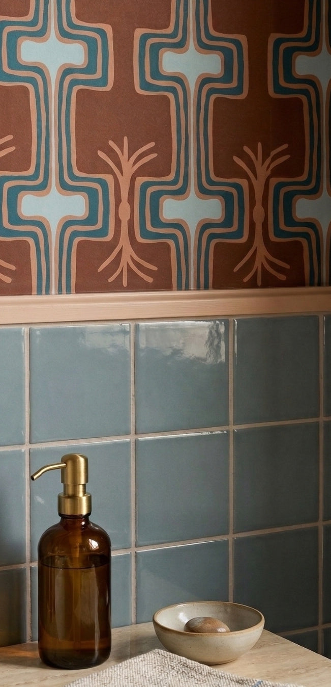 Muted blue-green glossy 4x4 solid tiles by Clay Imports, installed in a bathroom below patterned wallpaper.