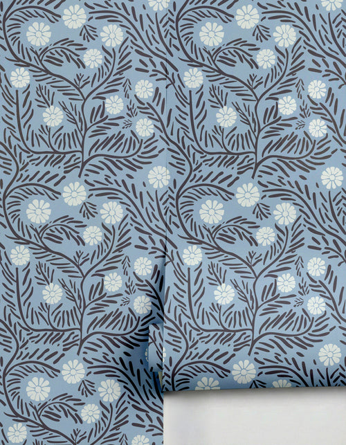 Silvestre Wallpaper by Clay Imports featuring a light blue background with dark botanical vines and white flowers, partially unrolled.