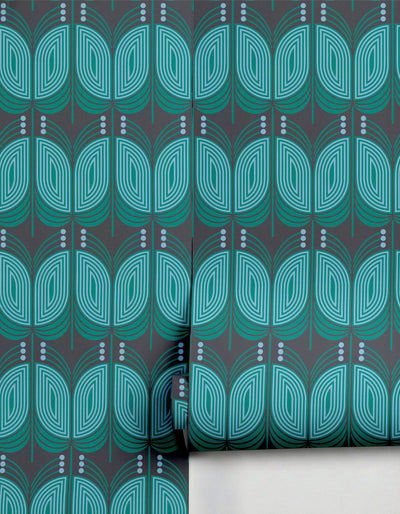 Dark grey wallpaper with a stylized teal and light blue geometric leaf pattern by Clay Imports, partially unrolled.