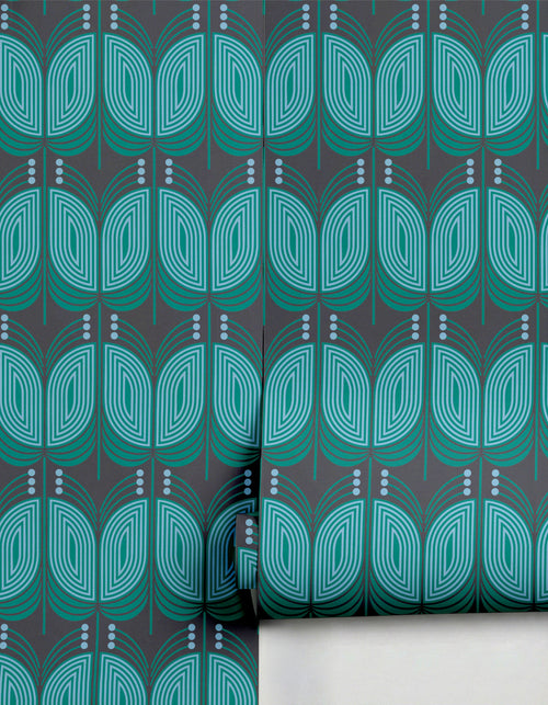 Dark grey wallpaper with a stylized teal and light blue geometric leaf pattern by Clay Imports, partially unrolled.