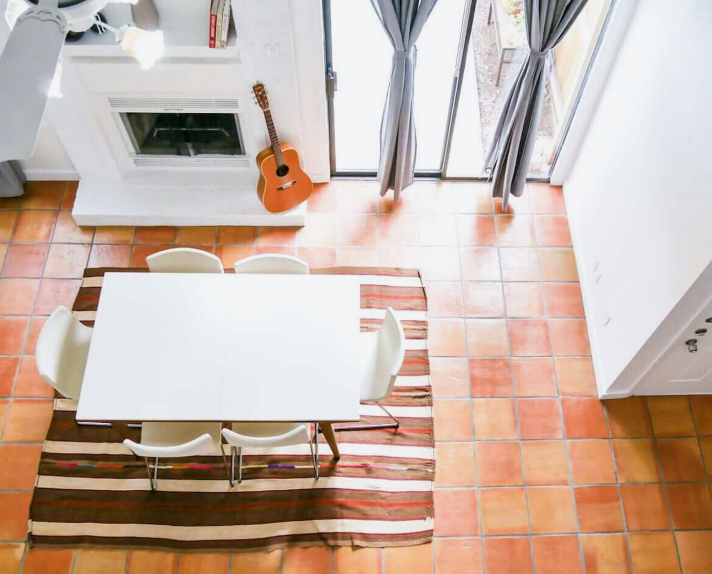 Warm reddish-brown 12x12 Antique Gloss terracotta tiles by Clay Imports, forming a floor in a dining room.