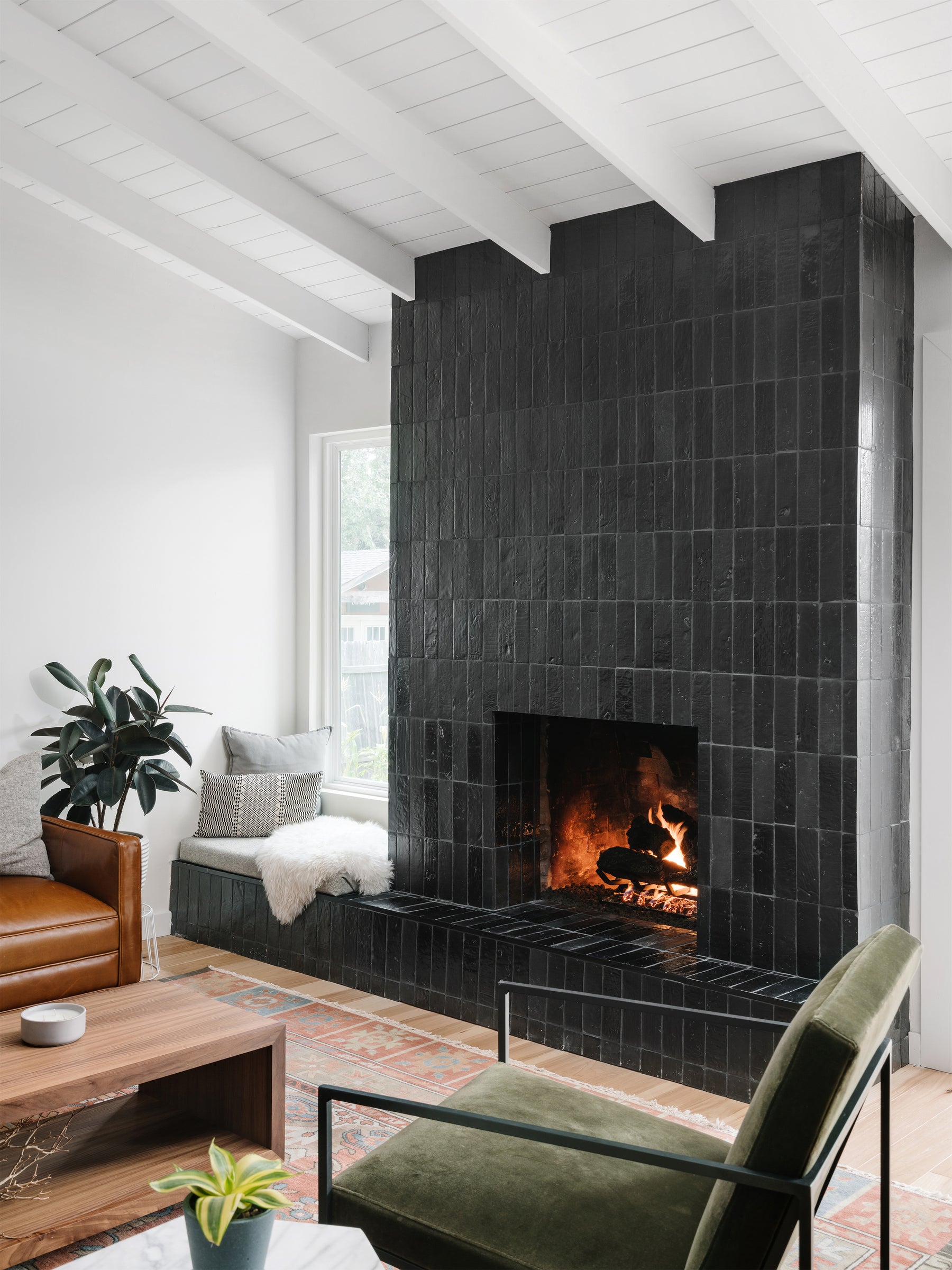 Glazed Thin Brick in Noir Black 2.5x8 by Clay Imports, applied vertically to a modern fireplace with a white beamed ceiling.