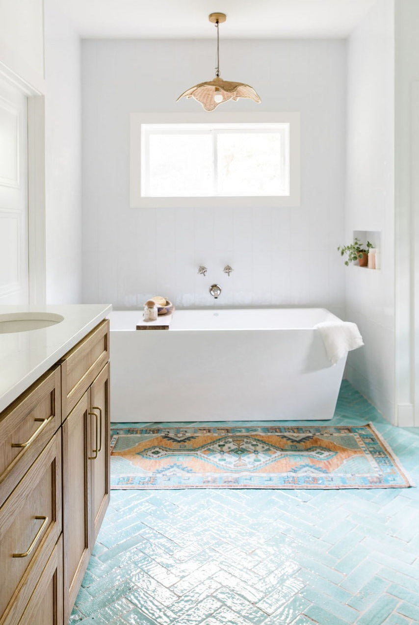 Light green glazed thin brick from Clay Imports installed in a herringbone pattern on a bathroom floor.