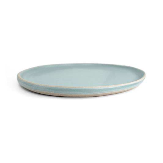 Light blue ceramic dinner plate by Clay Imports with a visible unglazed beige rim, on a white background.
