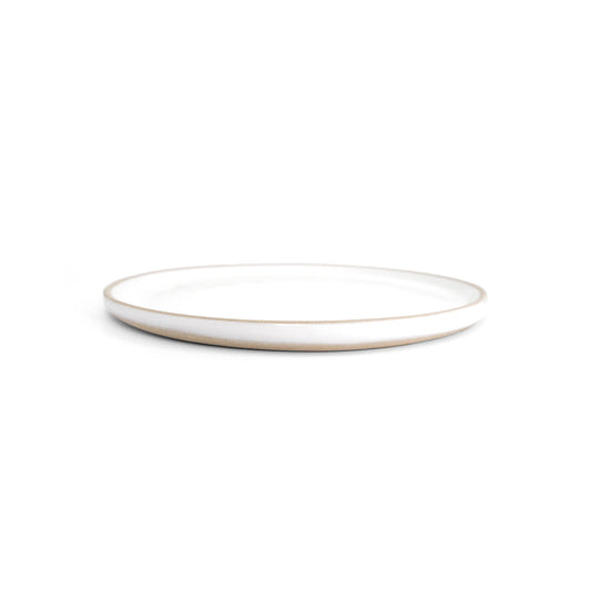 White glazed ceramic snack plate by Clay Imports with an exposed natural clay edge, viewed from a low angle.