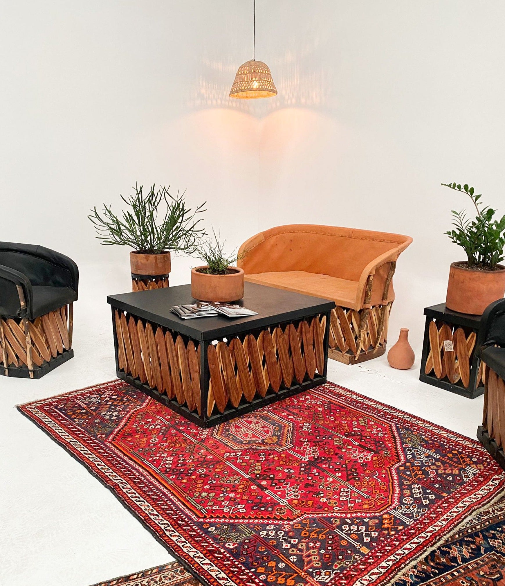 Square Box Coffee Table by Clay Imports with a black top and natural wood slat sides, styled on a red patterned rug.