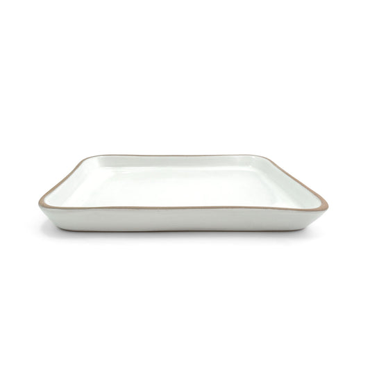 Shallow rectangular white-glazed tamale tray by Clay Imports with an unglazed brown rim, shown from a side angle.